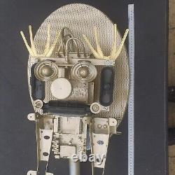 Tête de robot unique en métal recyclé avec des pièces de satellite peintes en or et une grande vis.